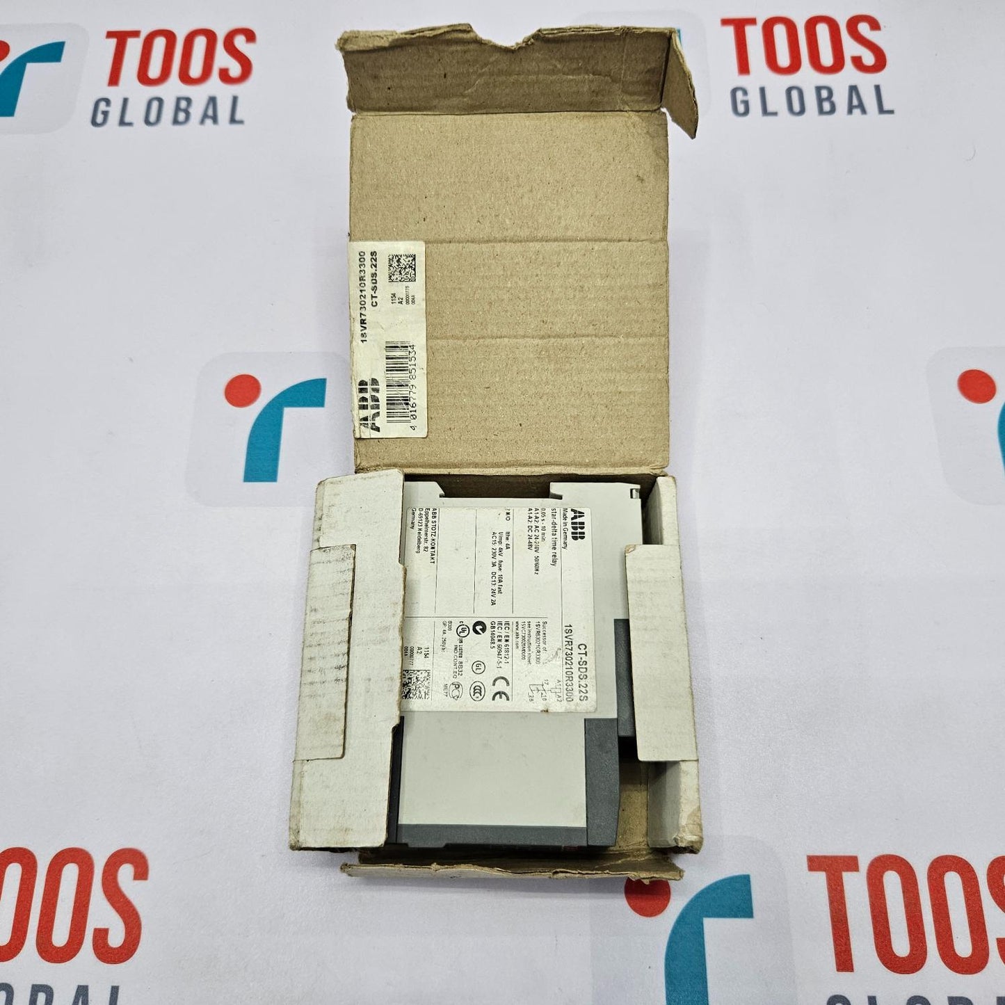 Electrical component in an open cardboard box on a TOOS GLOBAL branded background