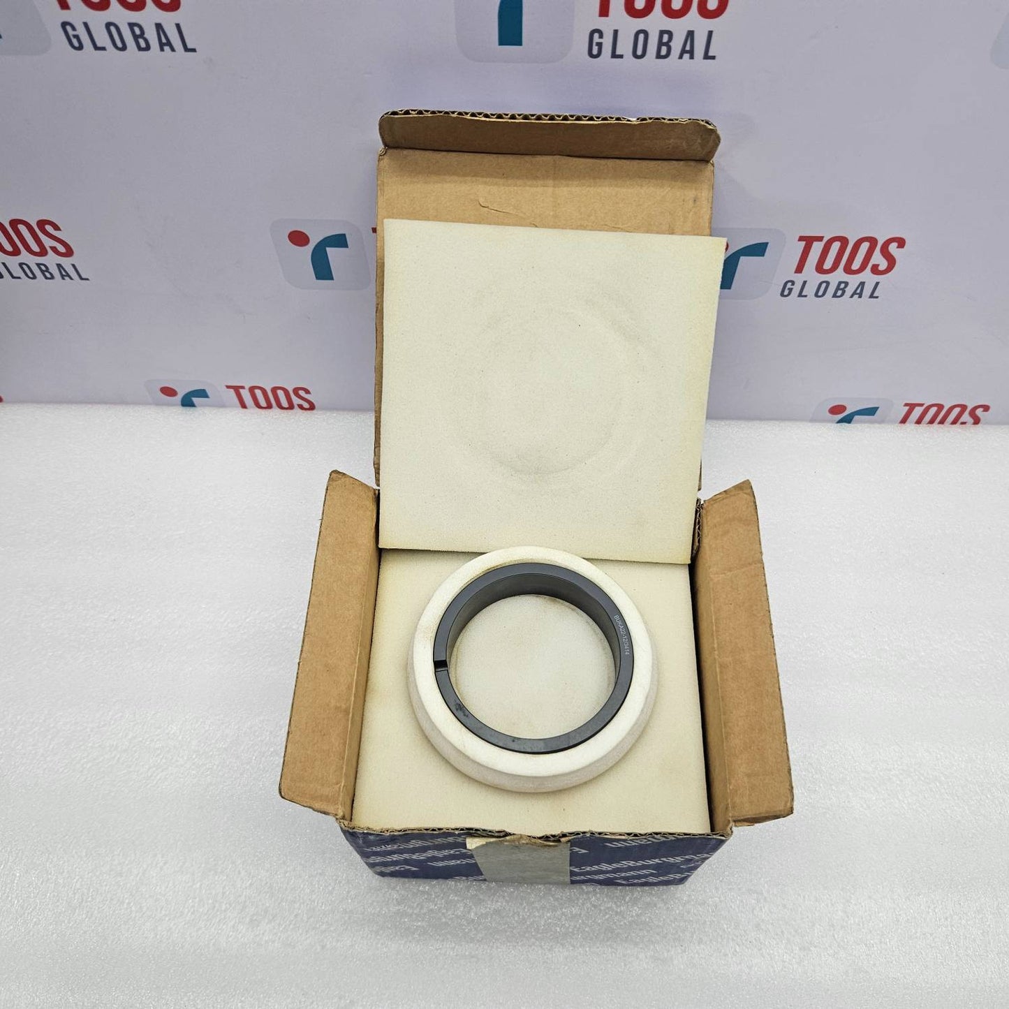 Mechanical bearing in an open cardboard box with a branded background