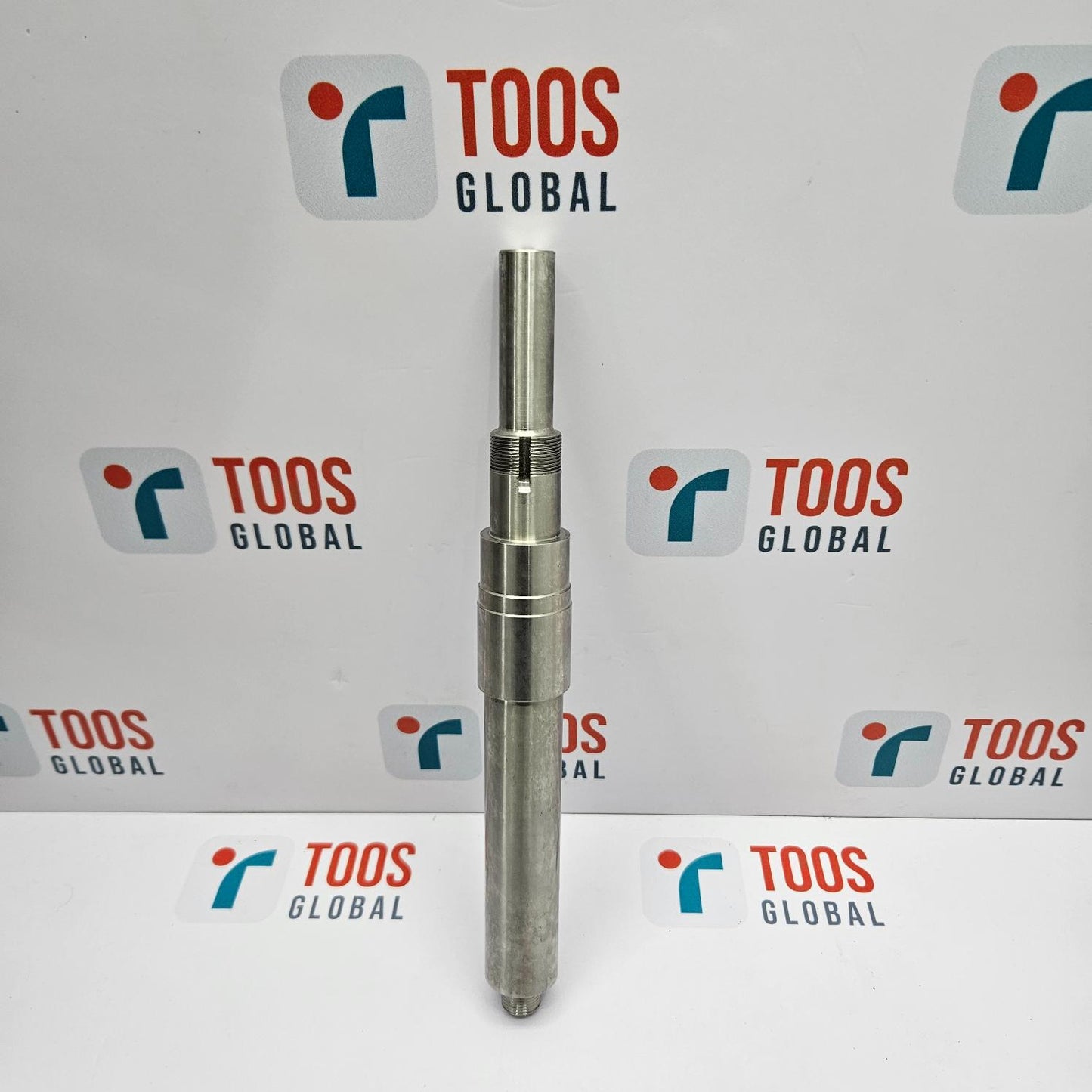 Metal cylindrical object with 'TOOS GLOBAL' branding in the background
