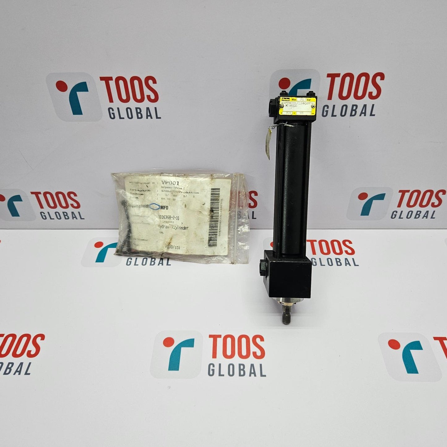 PARKER MC-M1100 PNEUMATIC CYLINDER packaged in a white plastic bag with a label, placed next to the cylinder which is black with a yellow label, on a background with the TOOS GLOBAL logo.