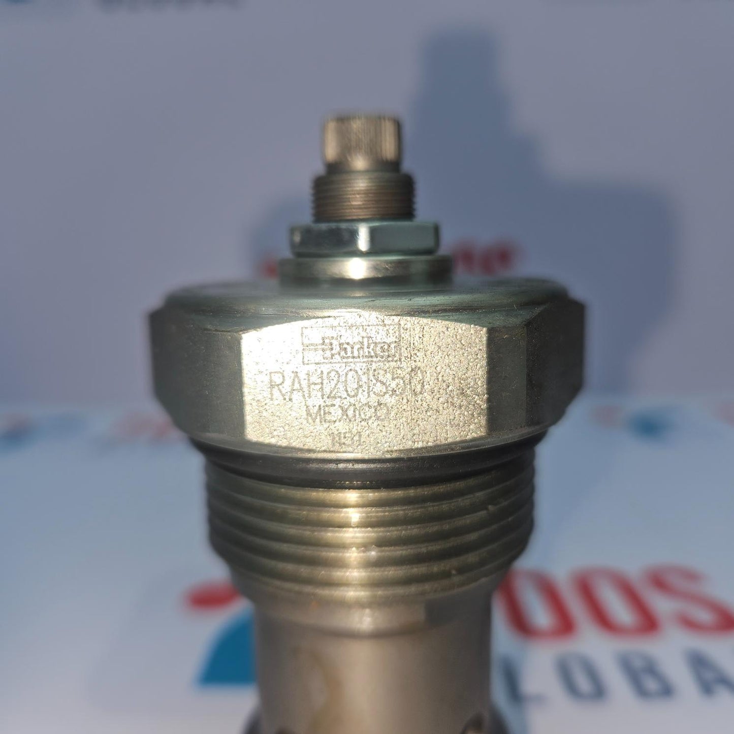 Metal valve or fitting with threading and a brand label on a blurred background