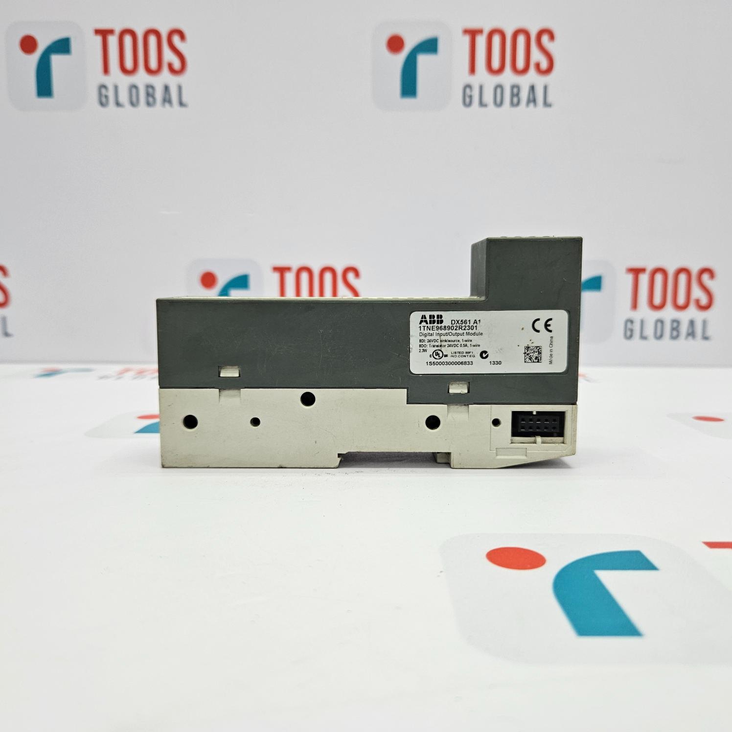 An ABB DX561 A1 Digital Input/Output Module, with a gray body and a black label on the front, placed on a white surface with the TOOS GLOBAL logo in the background.