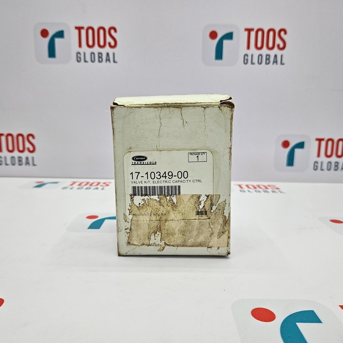Carrier Transicold Electric Valve Unloader 17-10349-00 Kit N The image shows a Carrier Transicold electric valve unloader kit in its original packaging, which is a cardboard box with visible signs of wear and marking, placed on a table with the brand name 'TOOS GLOBAL' visible in the background.