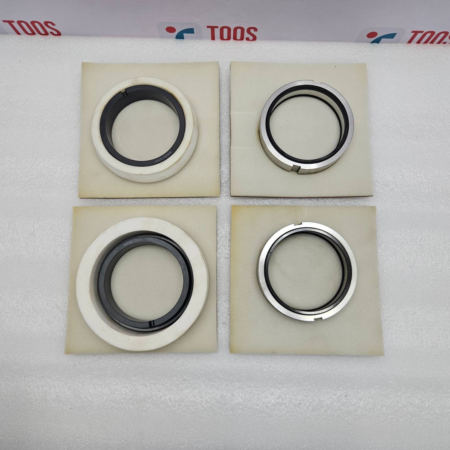 eagle burgmann Four mechanical seals on beige squares with 'TOOS' branding in the background.