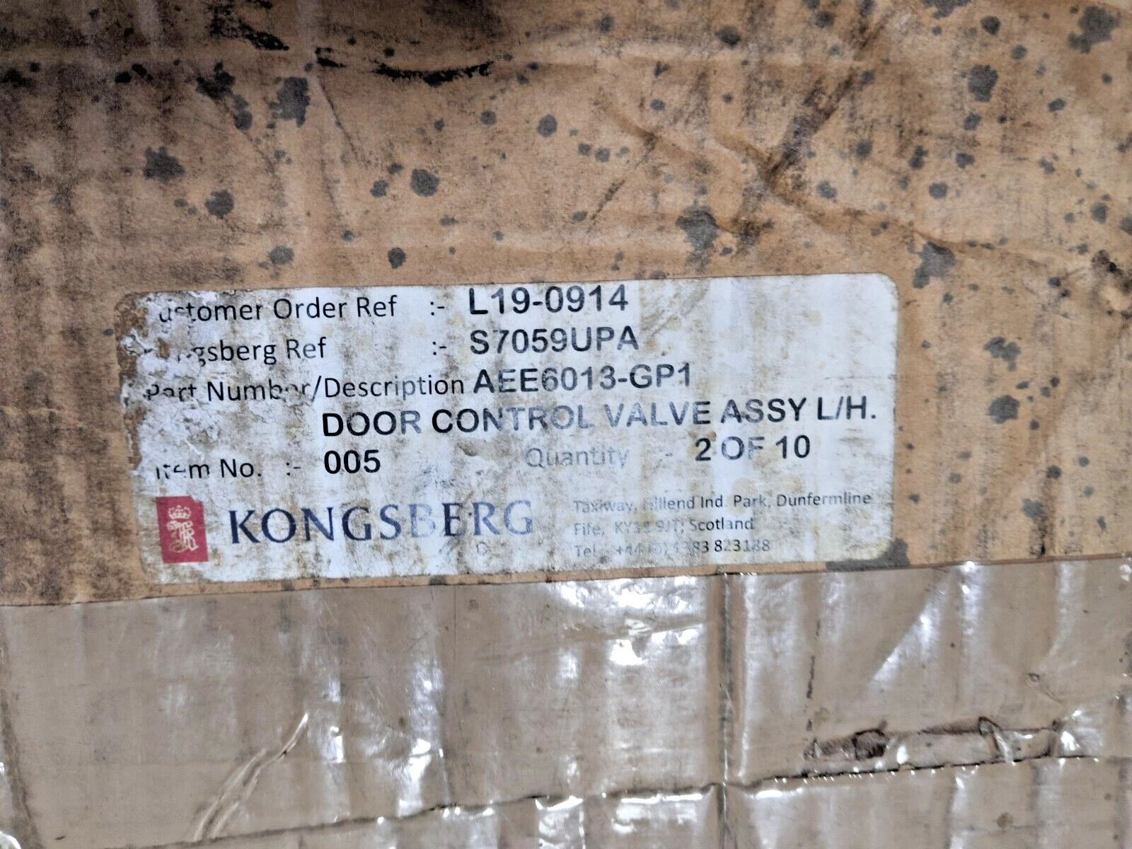 Kongsberg label on a cardboard box with text and a logo.