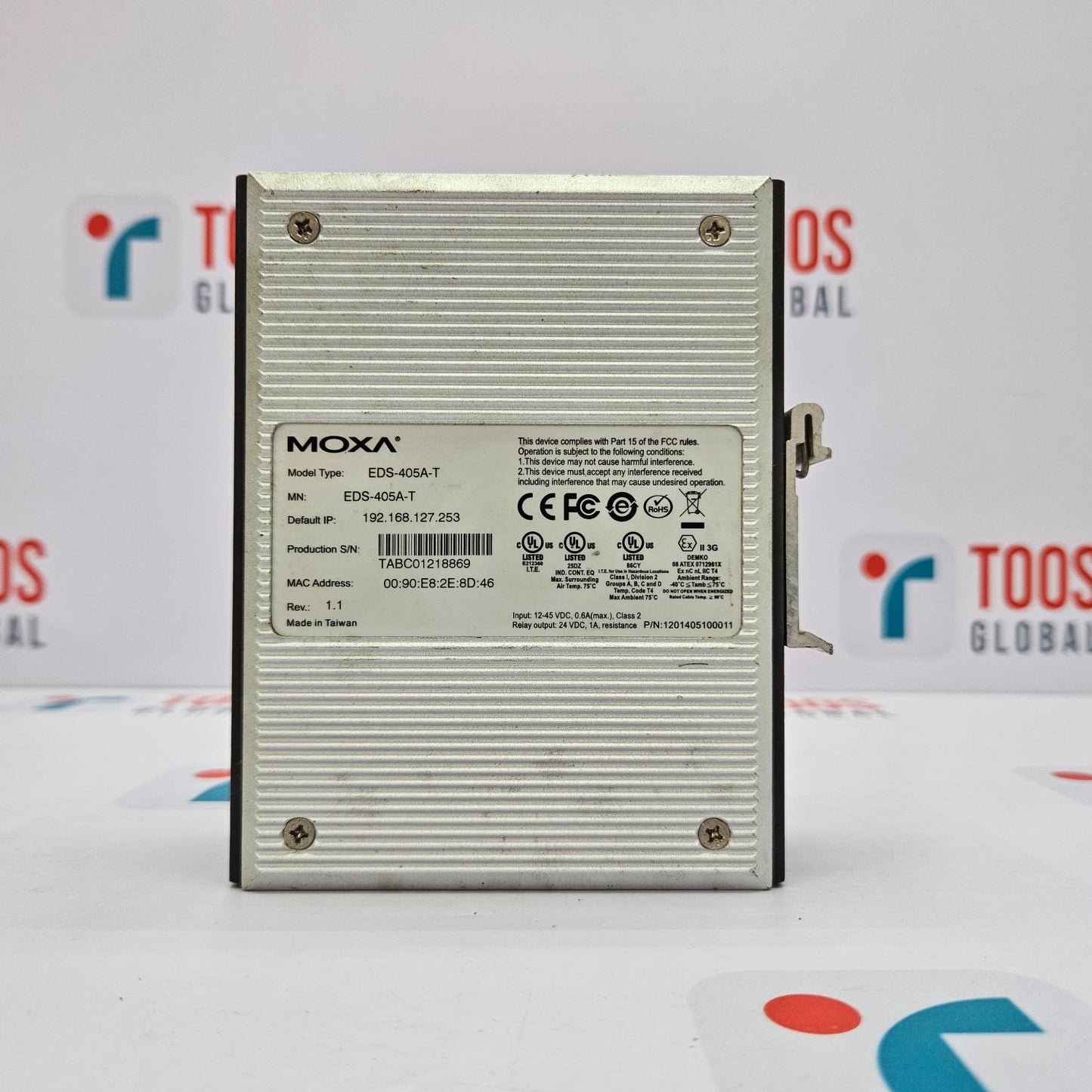 The image shows a MOXA EDS-405A-T 5-PORT ETHERNET DEVICE SWITCH, which is a silver-colored box with the brand and model details visible on the label.