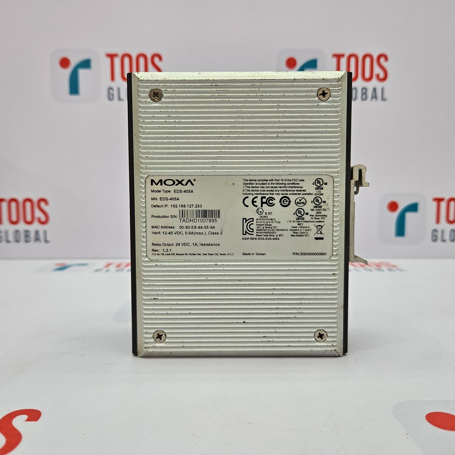 The image shows a MOXA EDS-405A Ethernet switch with 5 ports. The device is silver, with a metal casing and branding information visible on the front.
