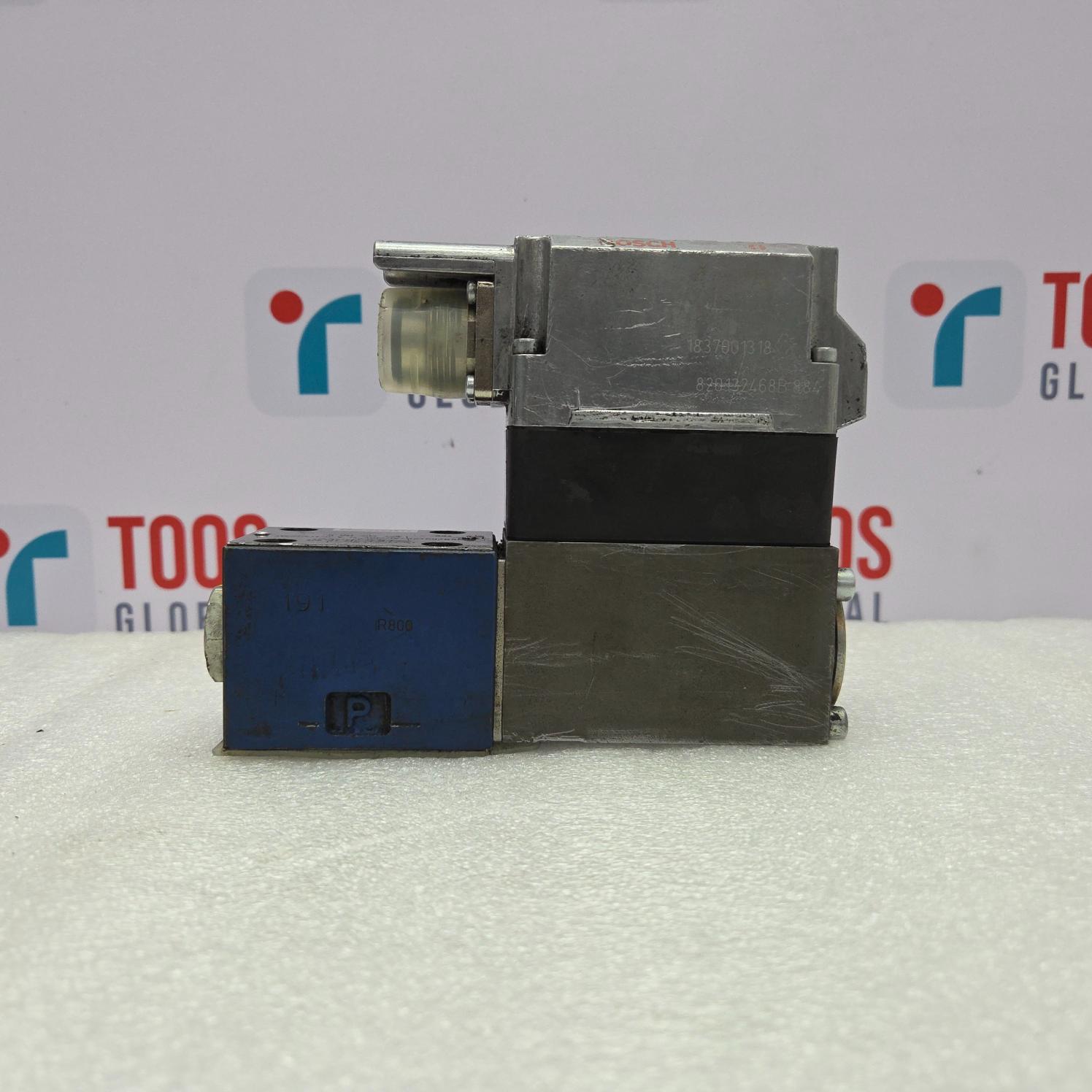 Rexroth 0811404720 Servo Valve on a white surface with a blurred background featuring logos.