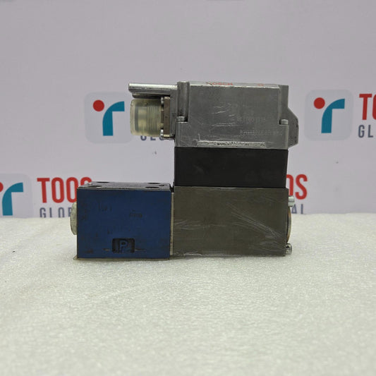 Rexroth 0811404720 Servo Valve on a white surface with a blurred background featuring logos.