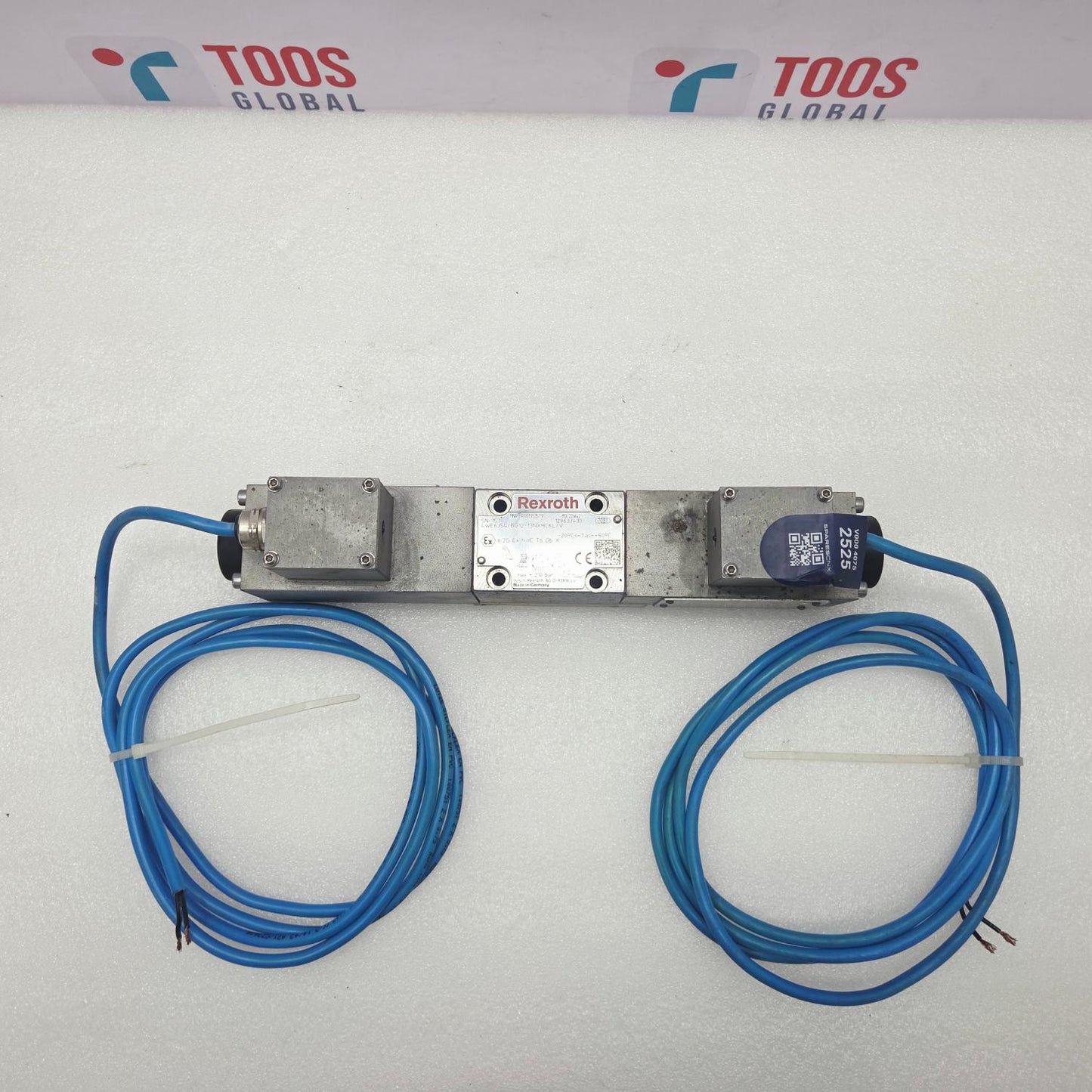 A pneumatic solenoid valve with a silver metal body, featuring a central red and white brand plate reading 'Brooks' and two blue pneumatic tubes connected to the ports, coiled on a white background with a TOOS GLOBAL header card.